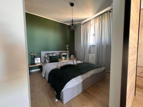 a bedroom with a bed and a green wall at Apartament M.55 in Gdynia