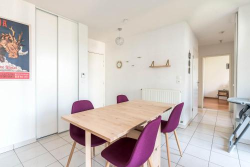 a dining room with a wooden table and purple chairs at La loge du Minotaure, parking et bureaux in Toulouse