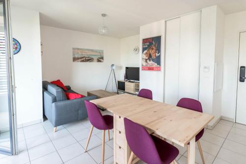 a living room with a wooden table and purple chairs at La loge du Minotaure, parking et bureaux in Toulouse
