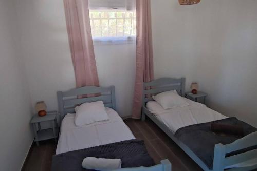 2 Betten in einem kleinen Zimmer mit Fenster in der Unterkunft F4 à Porticcio avec piscine et vue sur mer in Porticcio