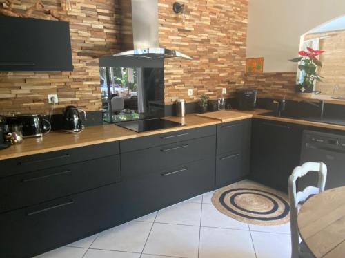 a kitchen with black cabinets and a sink and a counter at Villa piscine chauffée & spa sur le Bassin d Arcachon - proche plage et océan in Lanton
