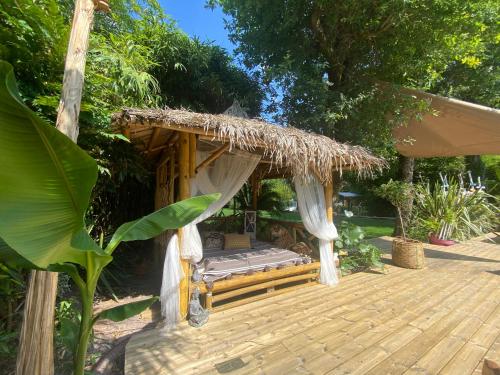 a wooden porch with a thatch roofed gazebo at Villa piscine chauffée & spa sur le Bassin d Arcachon - proche plage et océan in Lanton