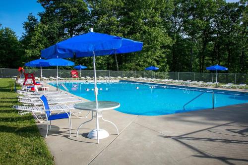 a pool with chairs and tables with blue umbrellas at 3E *Glamping at Treasure Lake* in DuBois