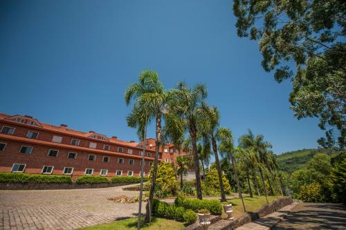 a building with palm trees in front of a street at Farina Park Hotel in Bento Gonçalves