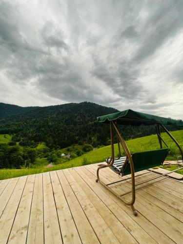 a green umbrella sitting on top of a wooden deck at Mitarbi Silence - cozy holiday cottages in mountains in Borjomi