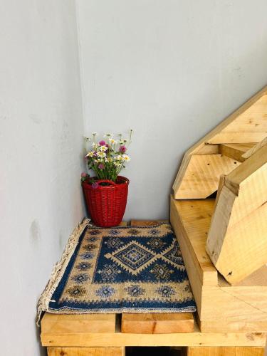a plant in a red basket sitting on a rug on a stairs at Mitarbi Silence - cozy holiday cottages in mountains in Borjomi