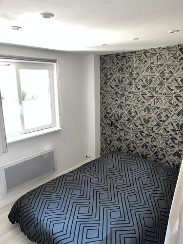 - une chambre dotée d'un lit avec un mur à motifs dans l'établissement Petite maison centre ville, à Chartres