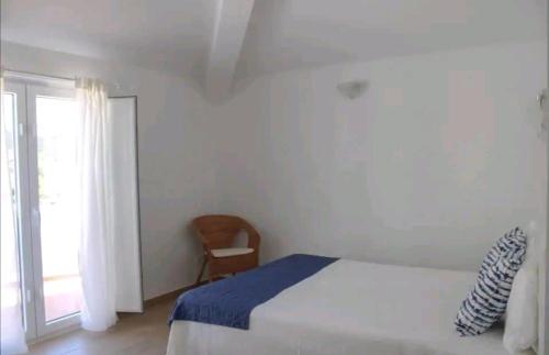 a bedroom with a bed and a window and a chair at Sudoeste Guest House in Odeceixe