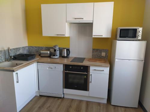 uma cozinha com armários brancos e um frigorífico branco em Forges 4 em Saujon