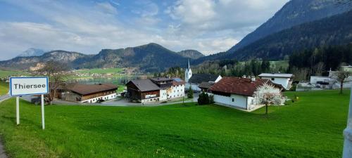 a group of houses in a green field with a sign at Ferienwohnungen Kirchenwirt in Thiersee