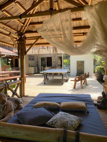 a patio with a ping pong table and a wooden roof at Villa piscine chauffée & spa sur le Bassin d Arcachon - proche plage et océan in Lanton