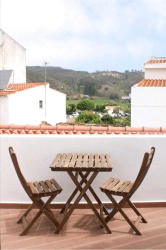 a picnic table and two chairs on a roof at Sudoeste Guest House in Odeceixe