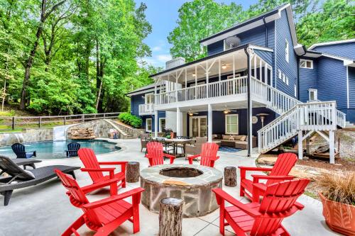 a patio with red chairs and a fire pit in front of a house at Lakefront, Saltwater Pool, Backyard Oasis, Private Dock, Home Gym in Flowery Branch