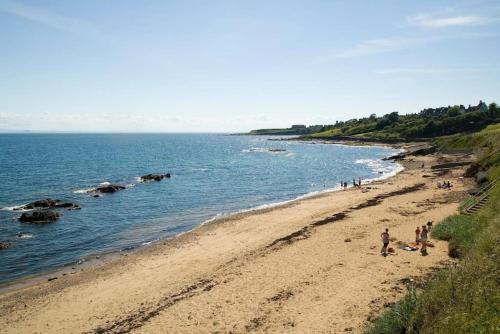 a group of people on a beach near the water at Beach House Walk - Crail - Home from Home in Crail