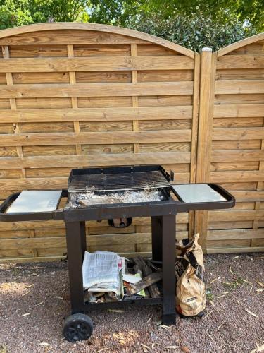 a picnic table with a b smoker on it in front of a fence at Villa piscine chauffée & spa sur le Bassin d Arcachon - proche plage et océan in Lanton