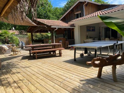 a ping pong table and bench on a deck at Villa piscine chauffée & spa sur le Bassin d Arcachon - proche plage et océan in Lanton