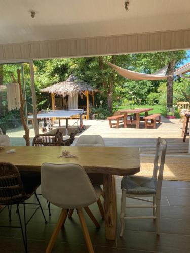 a large wooden table and chairs in a patio at Villa piscine chauffée & spa sur le Bassin d Arcachon - proche plage et océan in Lanton