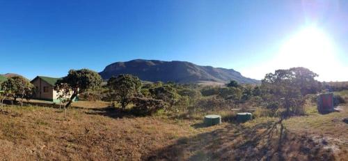 a field with a house and a mountain in the background at Pousada Morro da Baleia in Alto Paraíso de Goiás