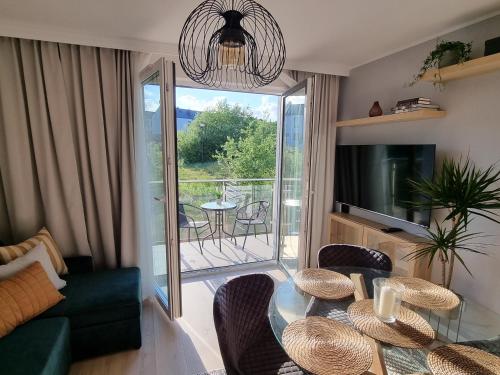 a living room with a table and chairs and a balcony at Apartament Młody Gdańsk - bezpłatny parking, mocne WiFi, dobre połączenie z lotniskiem in Gdańsk