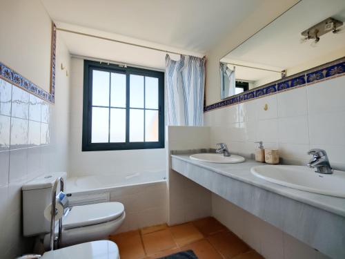 een badkamer met 2 wastafels, een toilet en een raam bij MIRADOR vacation home in Cala de Finestrat