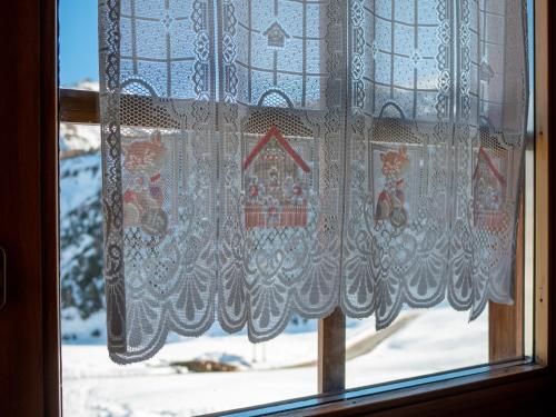 a curtain on a window with a snow covered yard at Bait Nof - Trepalle in Livigno