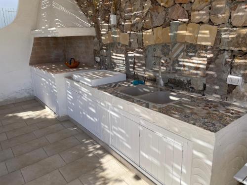 a kitchen with white counters and a sink at Calasetta casa al mare in Calasetta