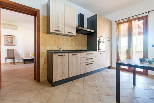 a kitchen with wooden cabinets and a table at Residence La Corte Di Anastasia in Torpè