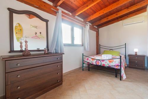a bedroom with a bed and a dresser and a window at Residence La Corte Di Anastasia in Torpè