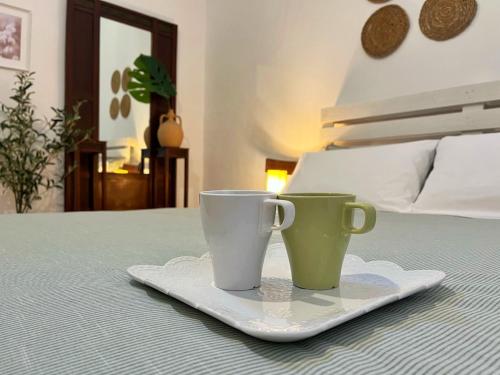 twee koffiekopjes zittend op een bord op een bed bij La Casetta in Muro Leccese