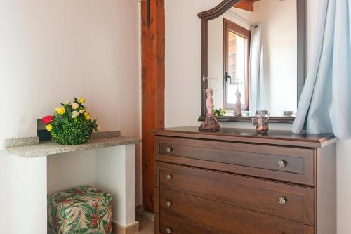 a bathroom with a wooden dresser and a mirror at Residence La Corte Di Anastasia in Torpè