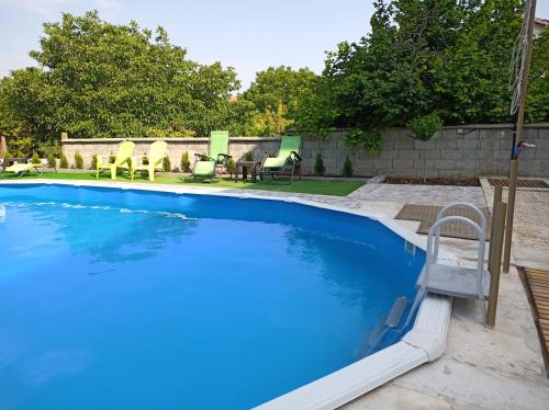a blue swimming pool with chairs and a table at Guest House 51 in Kranevo