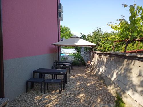 a group of tables and an umbrella next to a wall at Guest House 51 in Kranevo