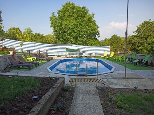 a swimming pool in a yard with chairs and tables at Guest House 51 in Kranevo