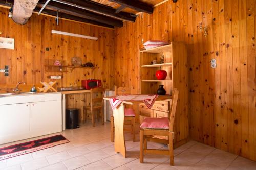 - une cuisine avec des murs en bois, une table et des chaises dans l'établissement Maison du bois, à Saint-Antoine