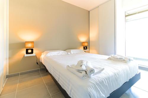 ein Schlafzimmer mit einem weißen Bett und Handtüchern darauf in der Unterkunft SELECT'SO HOME - Résidence Le Levant - Services hôteliers & Prestations de qualité - LEV41 in Le Lavandou