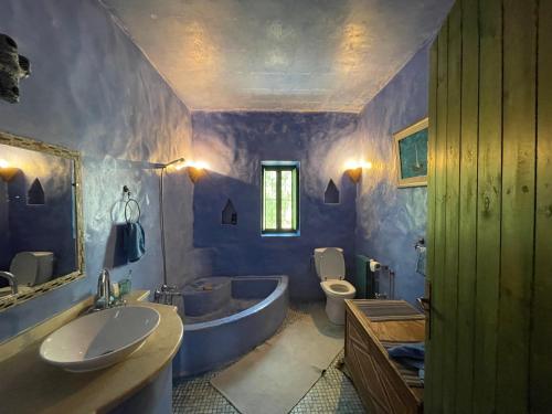 La salle de bains violette est pourvue d'une baignoire, de toilettes et d'un lavabo. dans l'établissement Menzel NOUR, à Mellita