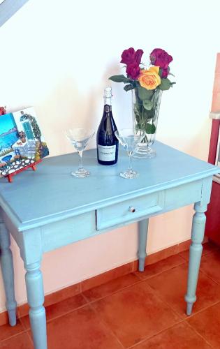 a blue table with two glasses and a bottle of wine at Odysseion Apartments in Vathi, Ithaka
