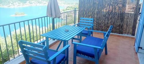 two blue chairs and a table on a balcony at Odysseion Apartments in Vathi, Ithaka
