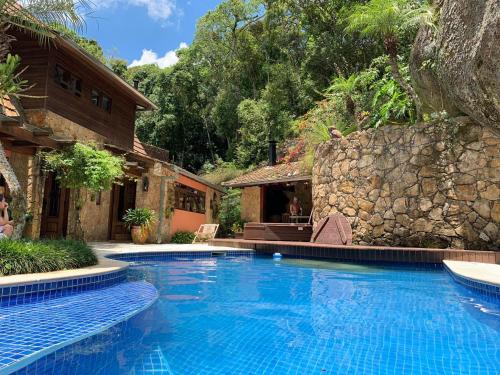 a swimming pool in front of a house at Casa da Pedra Atibaia Clube da Montanha in Atibaia