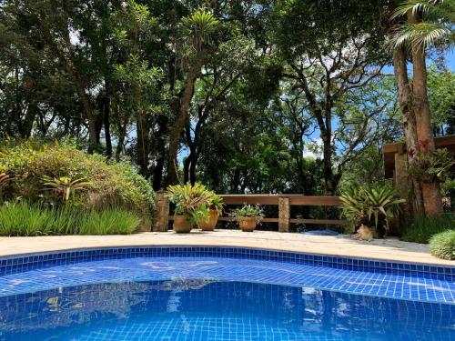 a swimming pool in a yard with potted plants at Casa da Pedra Atibaia Clube da Montanha in Atibaia