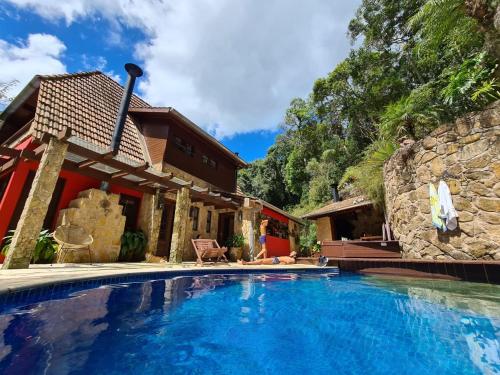 a woman sitting in a chair next to a swimming pool at Casa da Pedra Atibaia Clube da Montanha in Atibaia