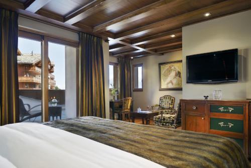 a bedroom with a bed and a flat screen tv at Guarda Golf Hotel & Residences in Crans-Montana