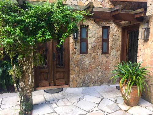 a stone house with a wooden door and two plants at Casa da Pedra Atibaia Clube da Montanha in Atibaia