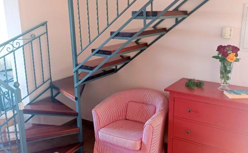 a living room with a chair and a staircase at Odysseion Apartments in Vathi, Ithaka