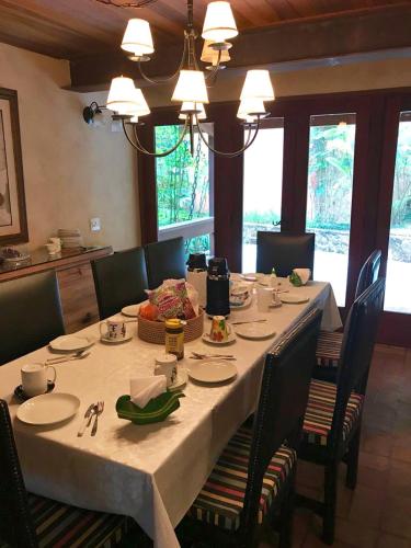 a dining room table with a white table cloth and chairs at Casa da Pedra Atibaia Clube da Montanha in Atibaia