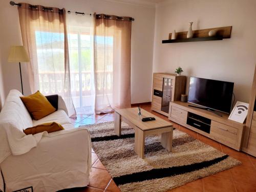 a living room with a couch and a tv and a table at Quinta dos Moledros in Figueira