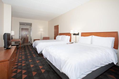 a hotel room with two beds and a television at Holiday Inn & Suites Goodyear - West Phoenix Area by IHG in Goodyear