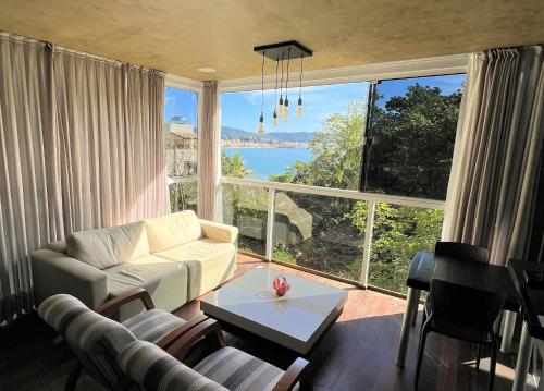 un soggiorno con un divano e una grande finestra di Refúgio da Lagoinha - Centro de Bombinhas a Bombinhas