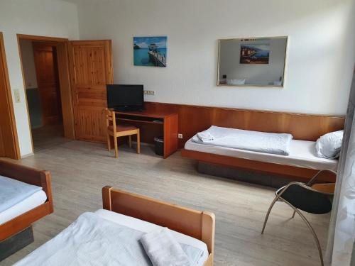 a room with two beds and a desk with a television at Stay2Night Hotel in Dillingen an der Saar