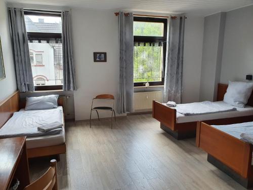 a room with two beds and two windows at Stay2Night Hotel in Dillingen an der Saar